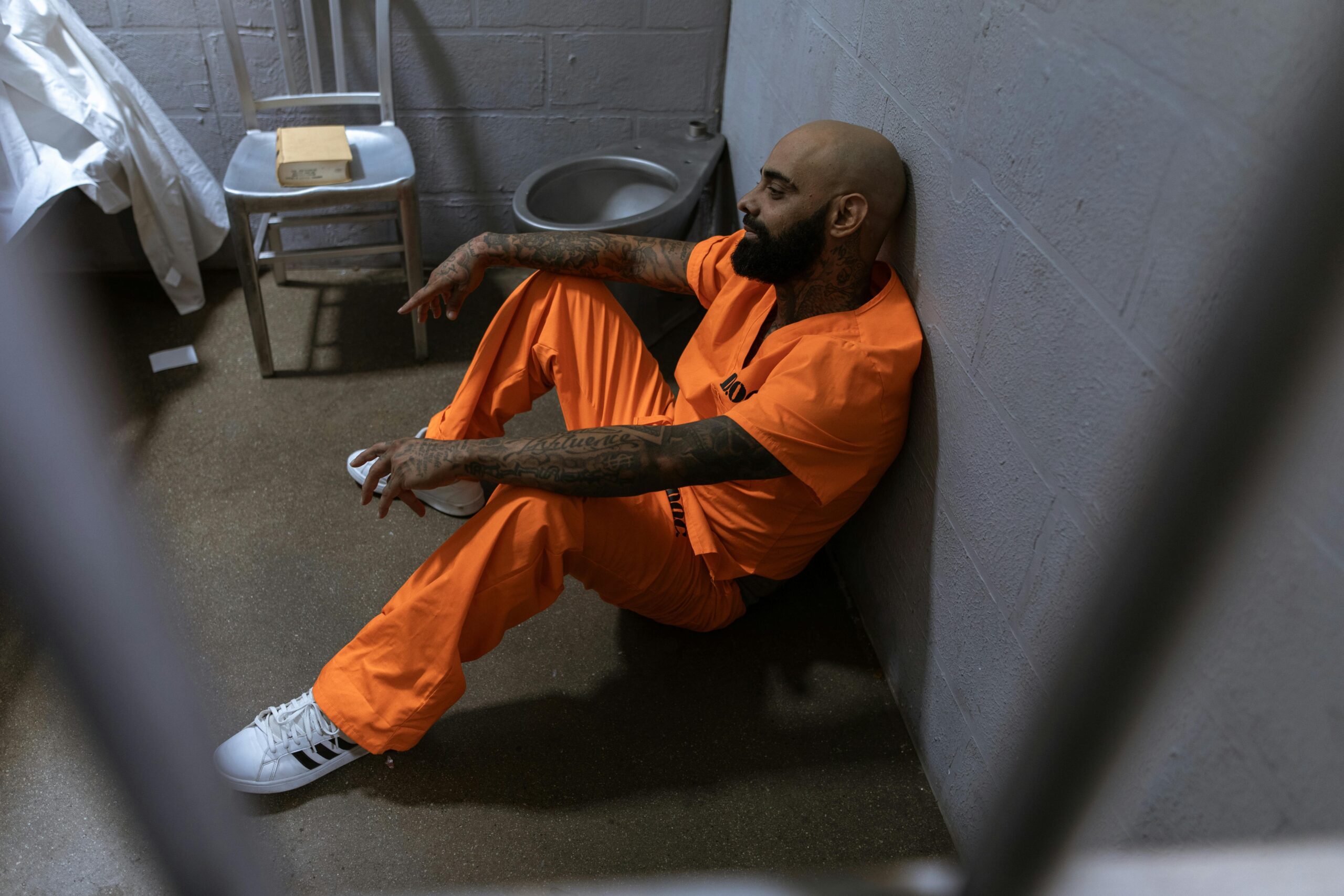 Man in Orange Shirt and Orange Pants Sitting on Floor